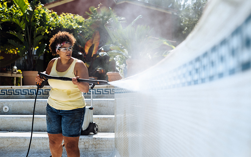 Woman cleans the tiles of a pool with a STIHL high-presure cleaner RE 110