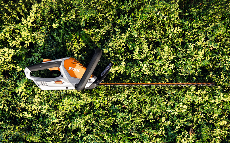 Cordless hedge trimmer STIHL HSA 45 lying on a hedge.